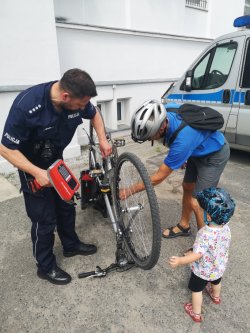 policjant znakuje rower w obecności obywatela