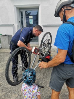 policjant znakuje rower w obecności obywatela